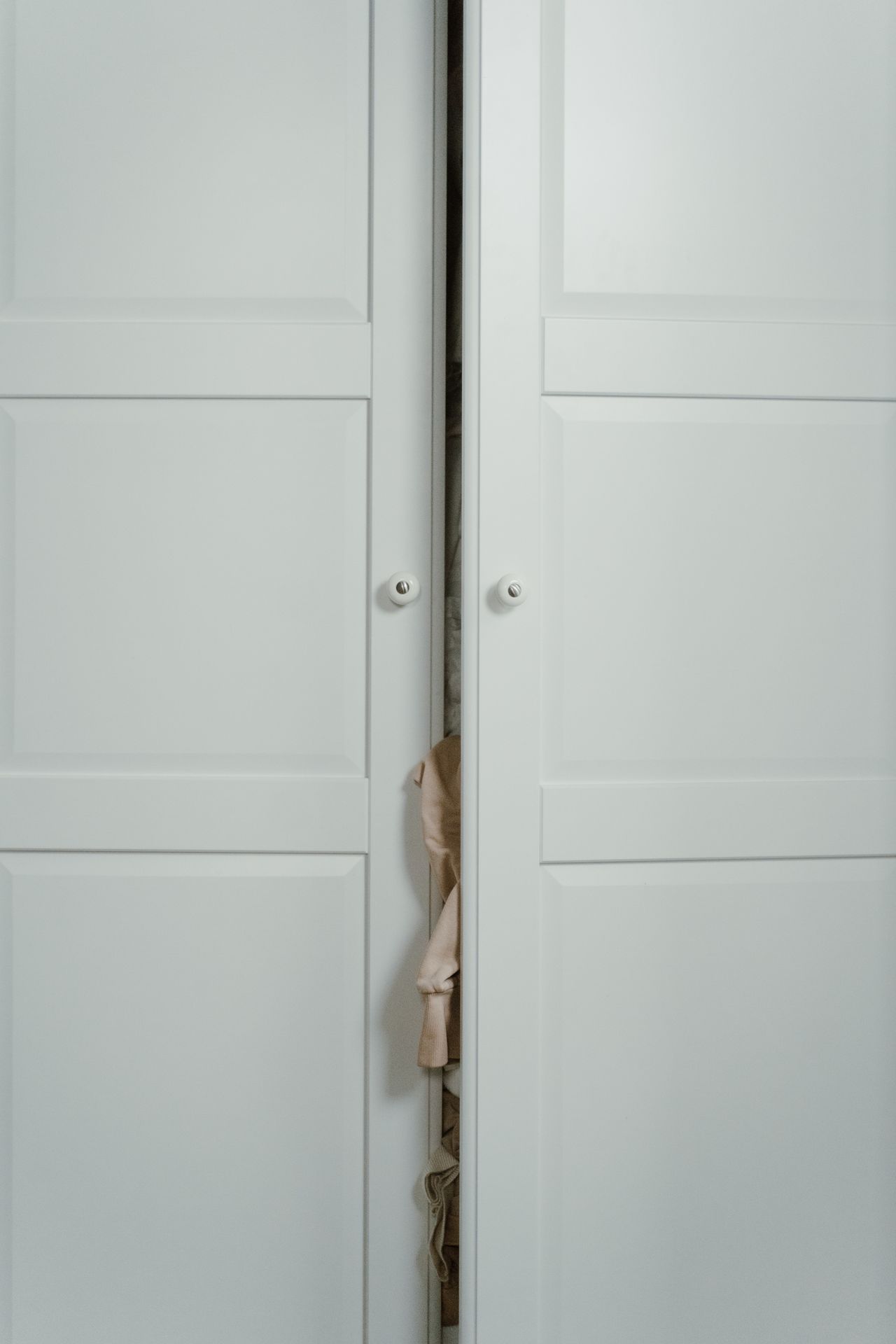 White wardrobe doors slightly open with small round knobs