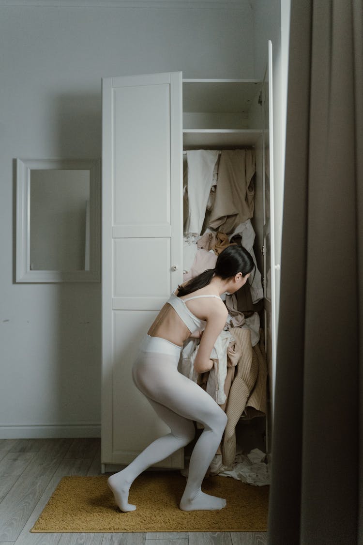 A Woman Getting Clothes In Cabinet