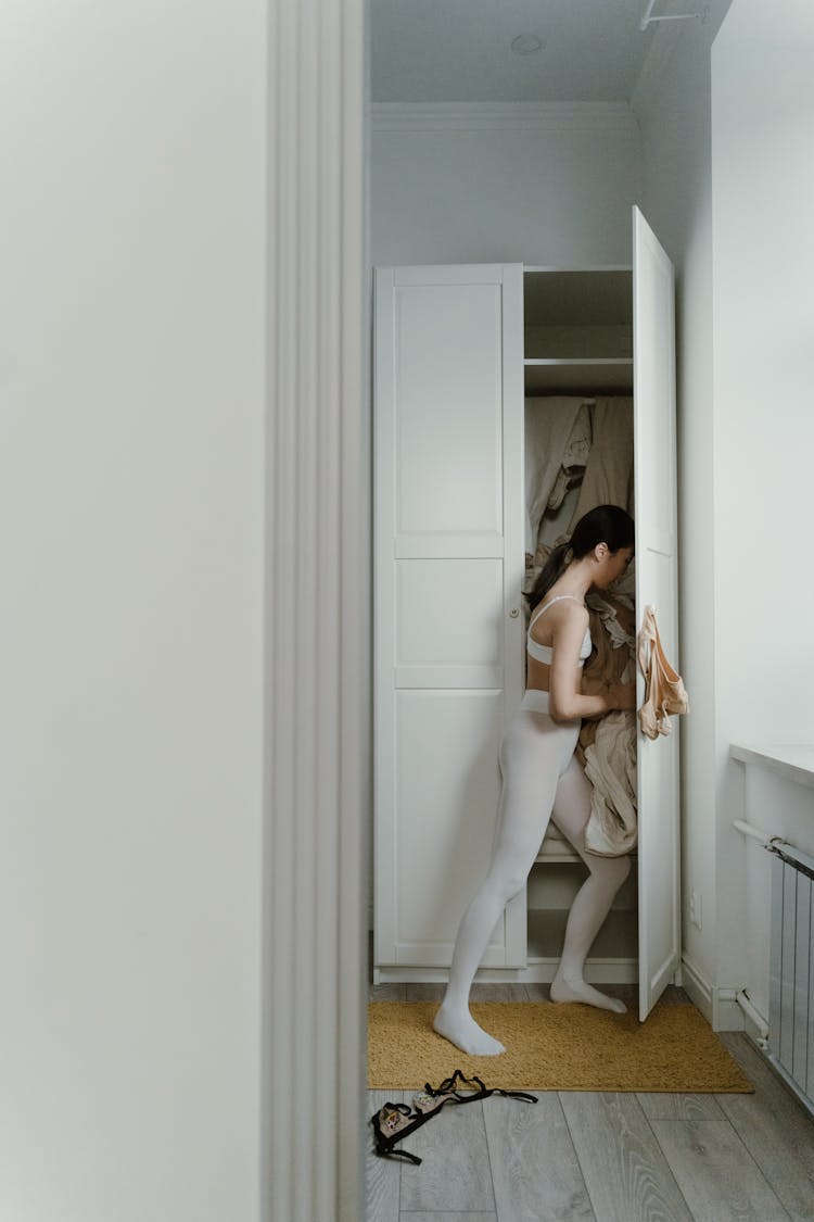 A Woman Getting Clothes In Cabinet