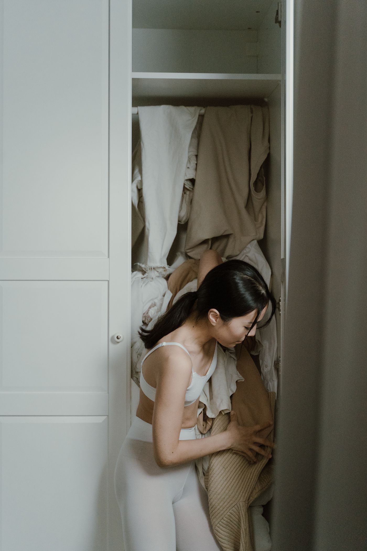 Woman looking through clothes already in her wardrobe