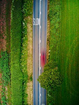Aerial view of a country road in England showing a green landscape and a moving vehicle with motion blur.