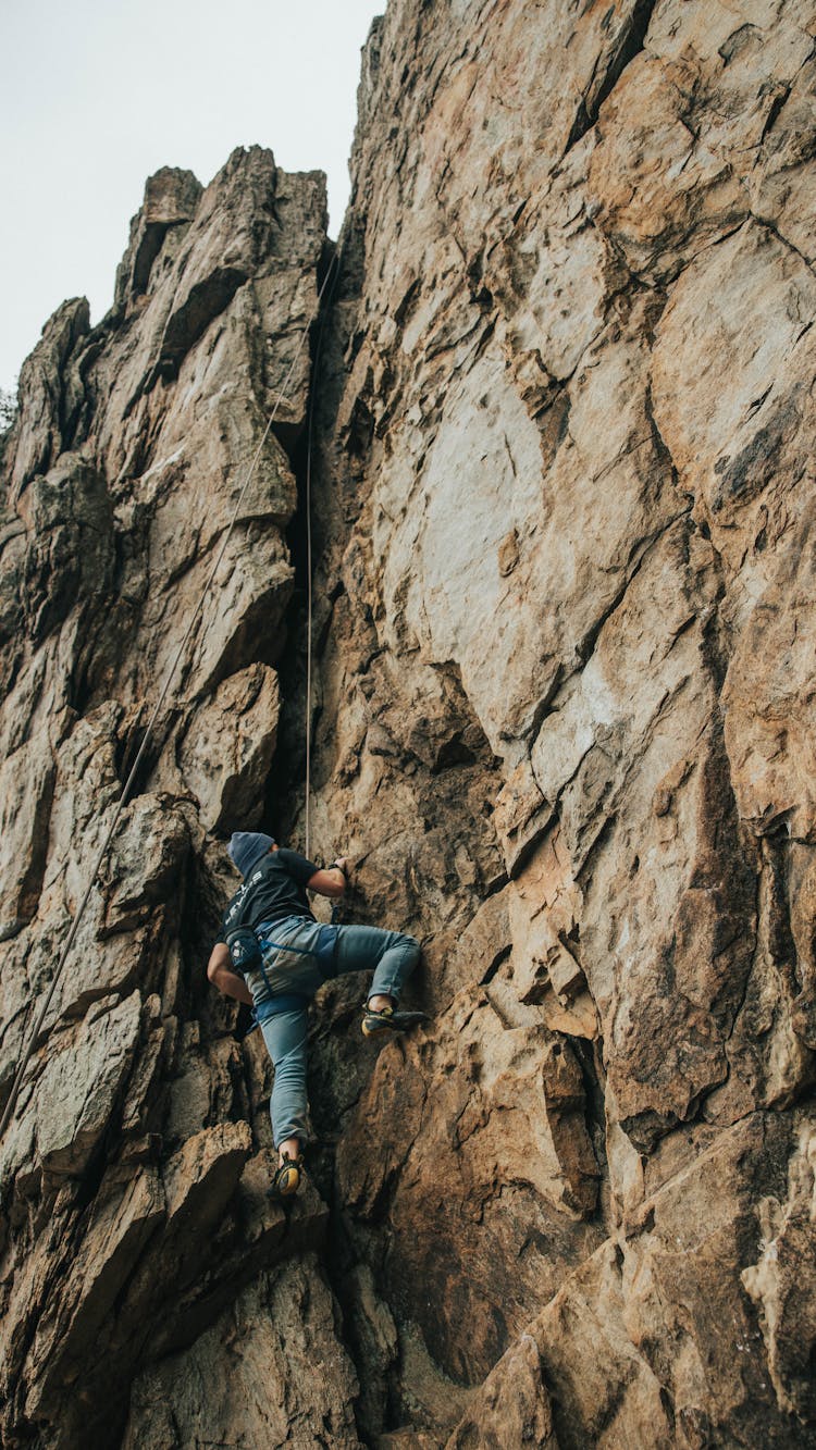 Man In Blue Jeans Climbing On Rocks