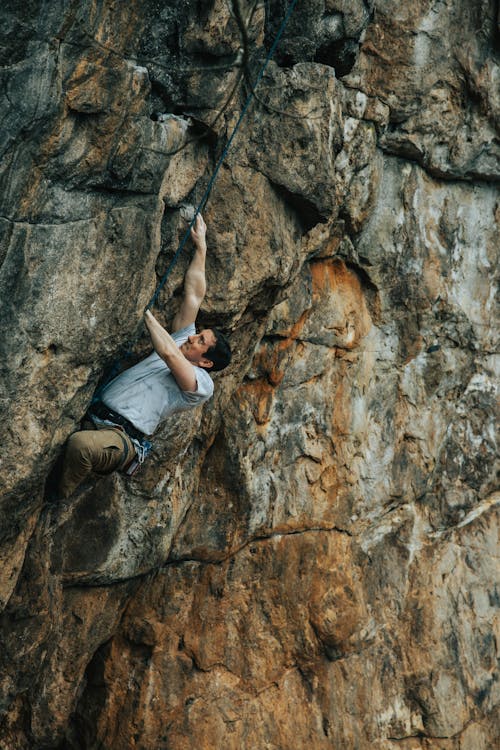 Man in Blue T-Shirt Climbing on Rocks