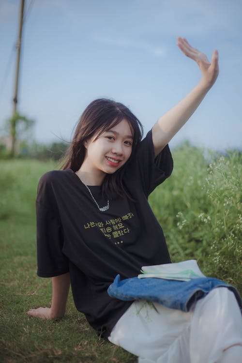 Woman in Black Crew Neck T-shirt Sitting on Green Grass Field