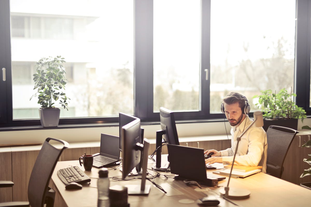 Mitarbeiter im modernen Büro arbeitet konzentriert am Computer mit Headset – digitale Kommunikation über das 5G-Netz.