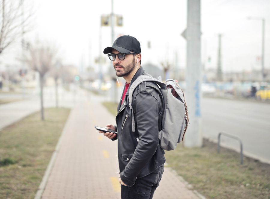 Man wearing a cap with a backpack on a city street