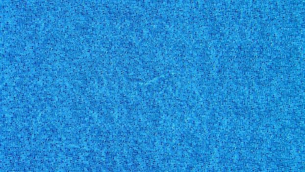 Close-up view of blue mosaic tiles covering a swimming pool surface.