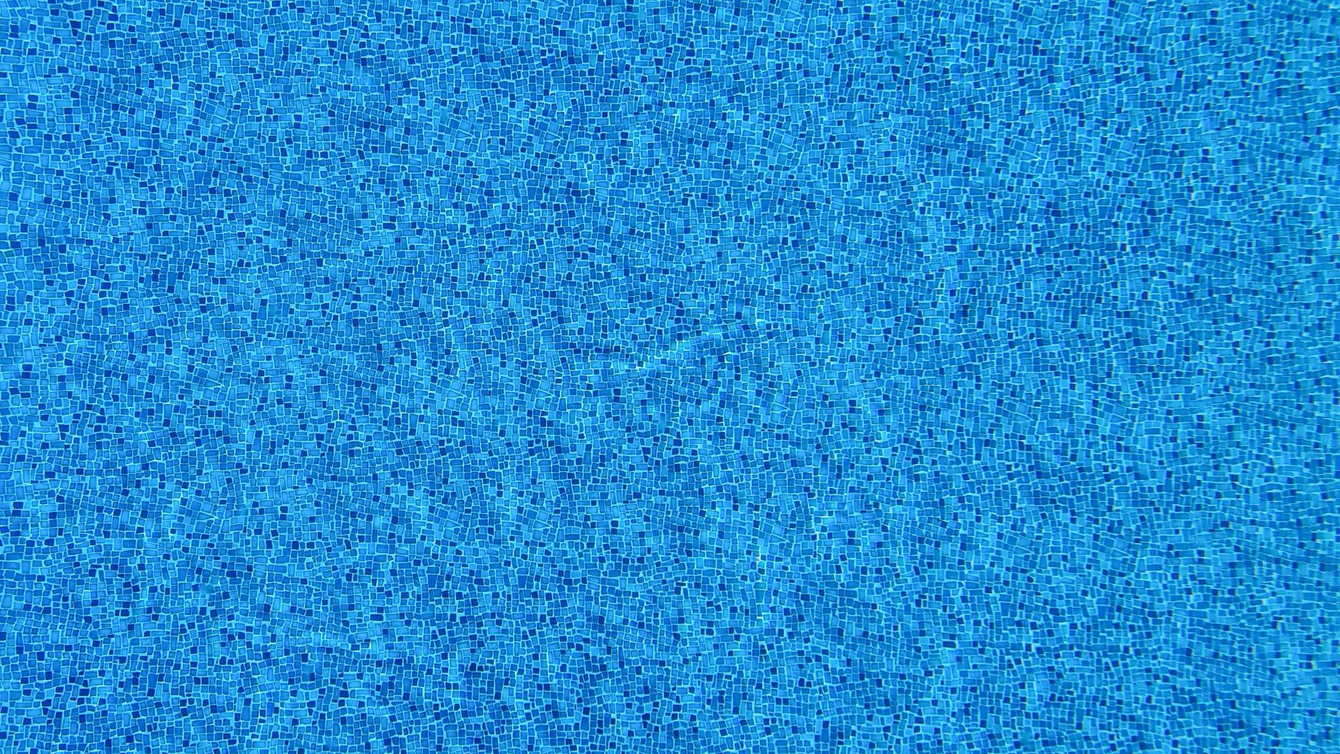 Close-up view of blue mosaic tiles covering a swimming pool surface.