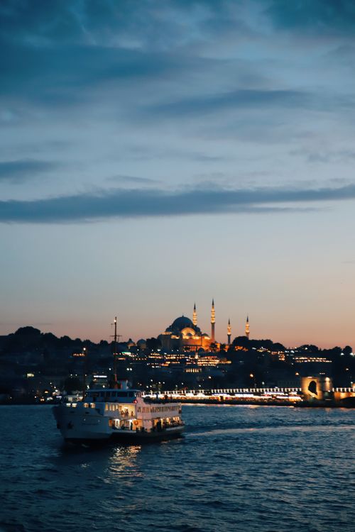 Free A serene view of Istanbul at dusk featuring an illuminated mosque and a ferry on the Bosphorus. Stock Photo