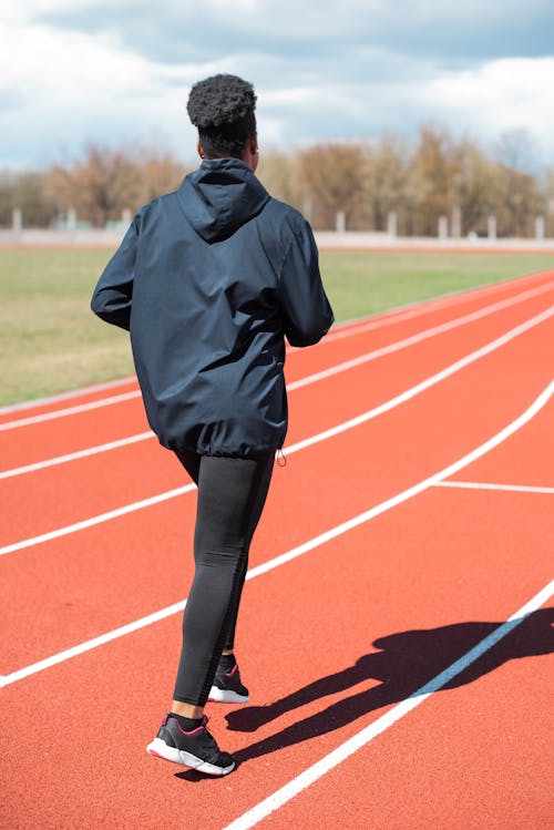 Woman Wearing a Hoodie Jacket Running on Track Field