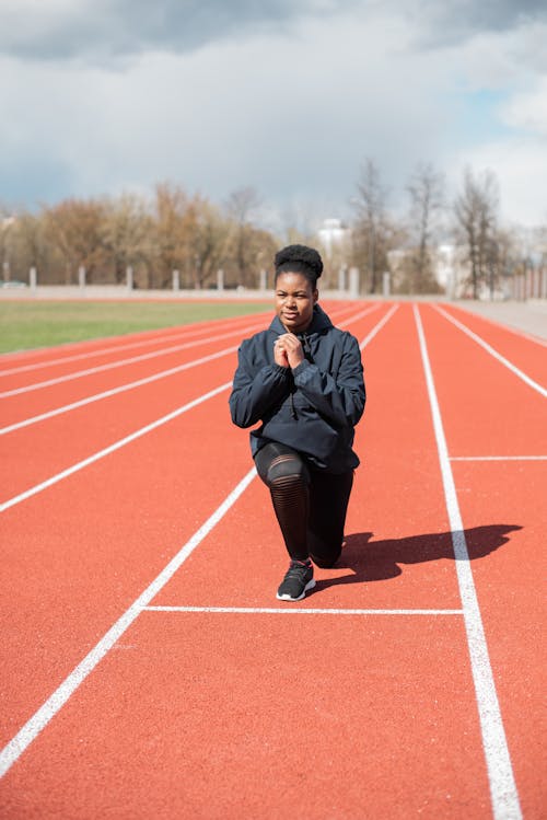 Free Woman in Black Sportswear Exercising on the Running Track Stock Photo