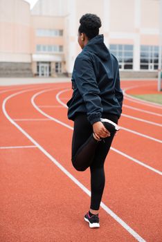 A woman is stretching on a track, showcasing fitness and determination.