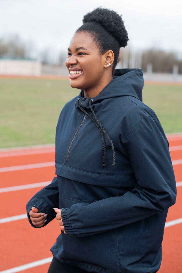 Woman Wearing A Hoodie Jacket While Jogging On The Track