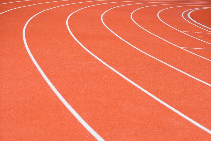 Curved lanes of a red running track — photo by Mikhail Nilov on Pexels