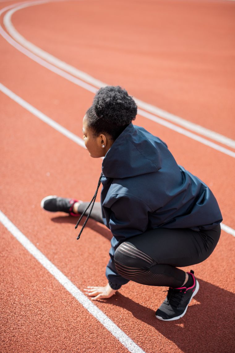 Athlete in activewear stretching on an outdoor running track — photo by Mikhail Nilov on Pexels