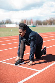 Black woman athlete in sportswear starting run on outdoor track.