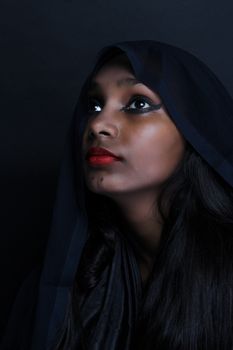 Captivating studio portrait of a woman with bold eyeliner and red lipstick against a dark background.