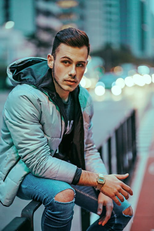 Man Sitting on Fence by Street