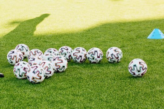 Soccer balls scattered on a green field with a training cone, ideal for sports-themed imagery.