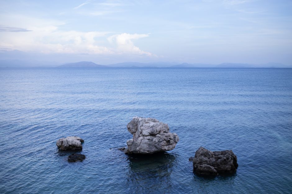 A peaceful seascape with rock formations under a clear blue sky, perfect for relaxation imagery.