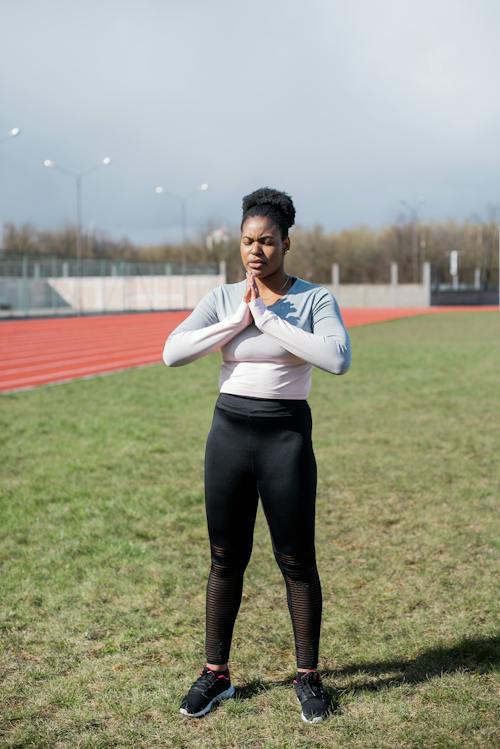 Woman Standing on Grass While Meditating