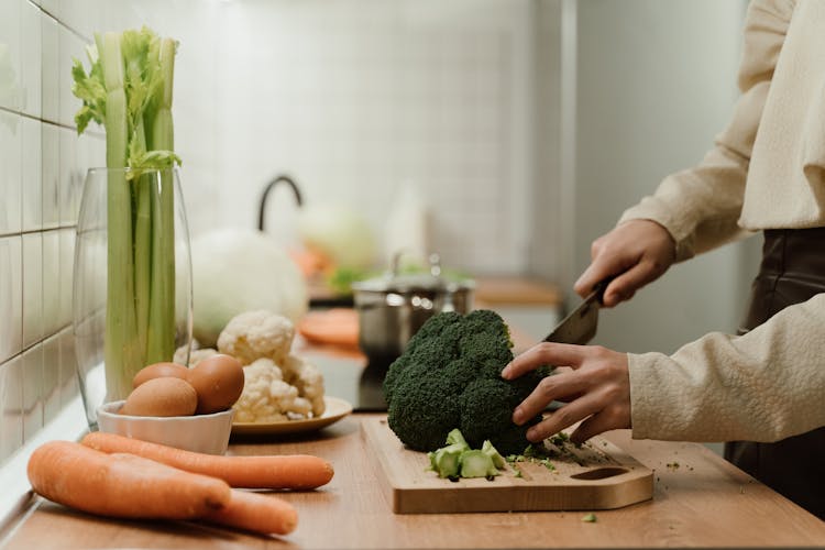 A Person Cutting Vegetables On The Wooden Cutting Board