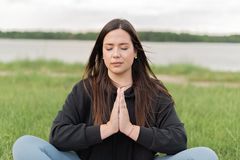 A serene woman practicing meditation outdoors near a lake, promoting wellness and relaxation.