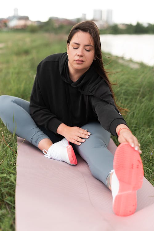 Free Woman in Black Hoodie Jacket Stretching on Yoga Mat  Stock Photo