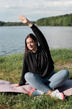 A woman enjoys a peaceful yoga session by a lakeside, promoting wellness and mindfulness.