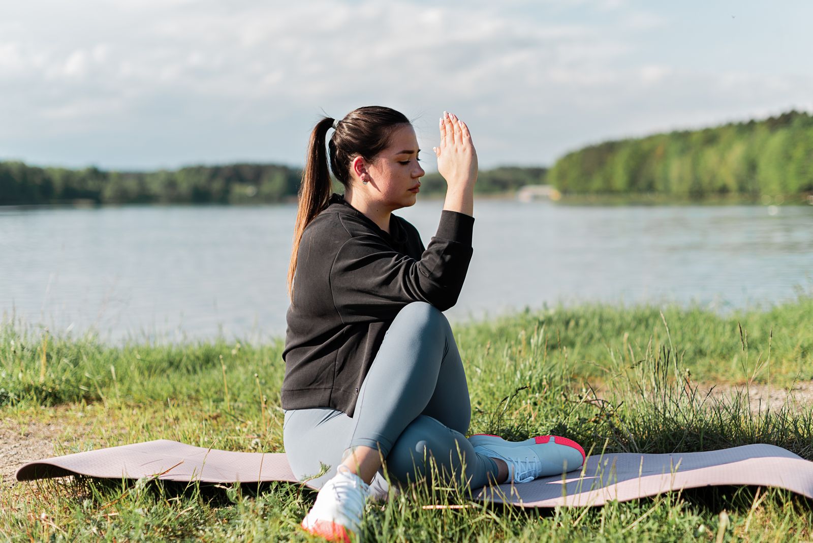 Woman meditating on a yoga mat by a calm lake for depression relief