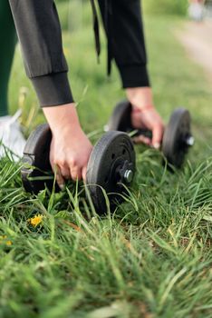 A person lifting dumbbells outdoors on grass, promoting fitness and healthy lifestyle.
