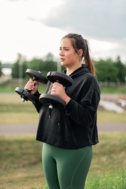 A Woman in Black Sweatshirt Lifting Weights