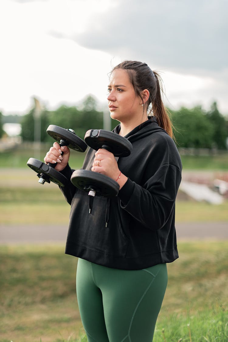 A Woman In Black Sweatshirt Lifting Weights