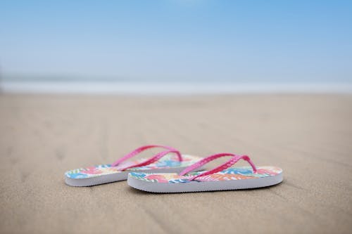 Pink and Blue Flip Flops on Brown Sand