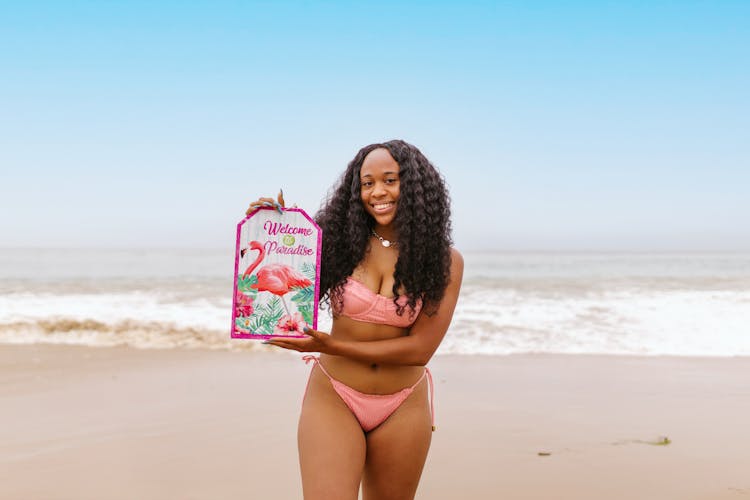 Woman In A Bikini On A Beach Holding A Board 
