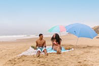 一对夫妇在海滩上打着伞和野餐设施享受阳光明媚的一天