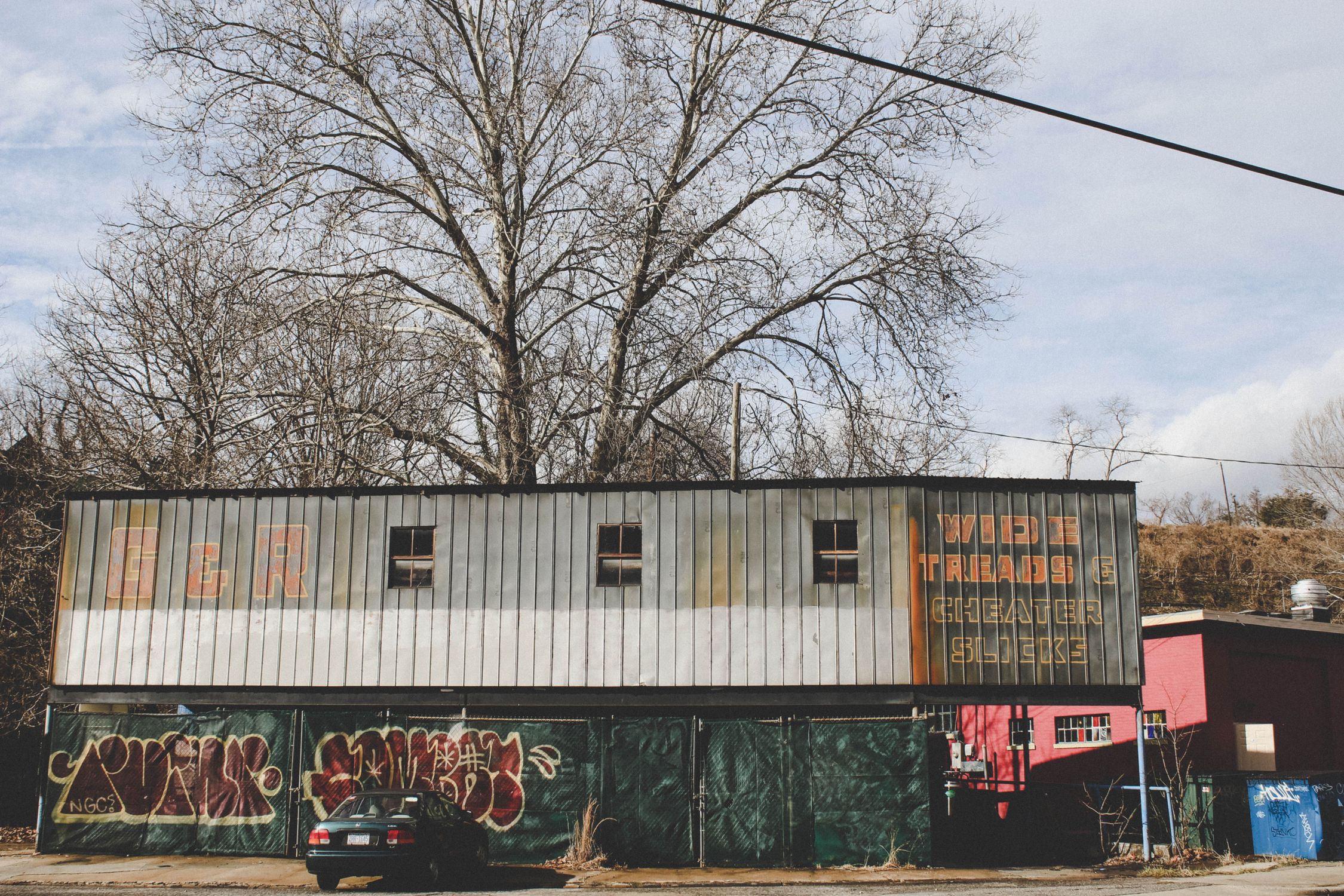 An old building with graffiti and abandoned car in Asheville, NC. Captures urban decay and street art.