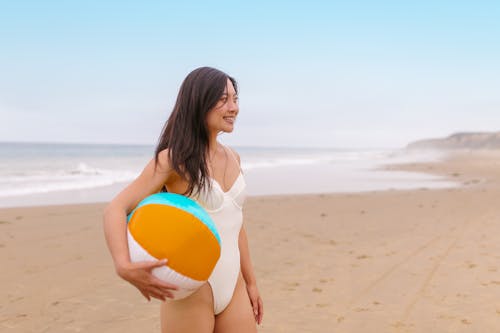 Woman in White Swimsuit Holding a Beach Ball