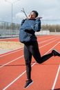 Woman in Black Jacket and Black Leggings Sitting on Track Field