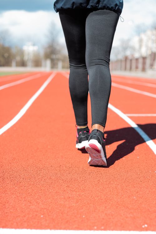 Free Close-up of a person jogging on a sunny day on an outdoor track, showcasing fitness and health. Stock Photo