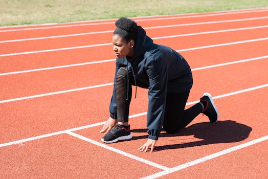 Female athlete in starting position on a sunny day at the track.