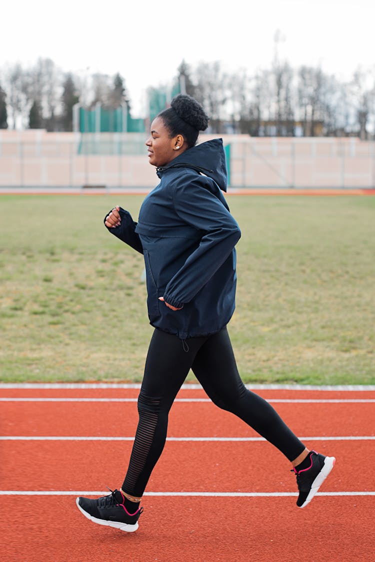 Woman In Sportswear Jogging In Track Field