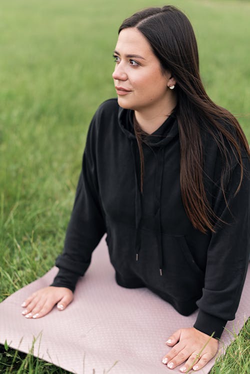 Free Woman in Black Hoodie Lying on Yoga Mat Stock Photo