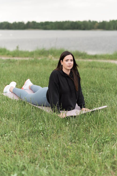 A Woman Exercising Over a Yoga Mat in the Grass