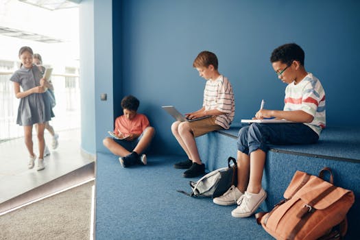 Group of students studying with laptops and notebooks in a cozy indoor school setting.