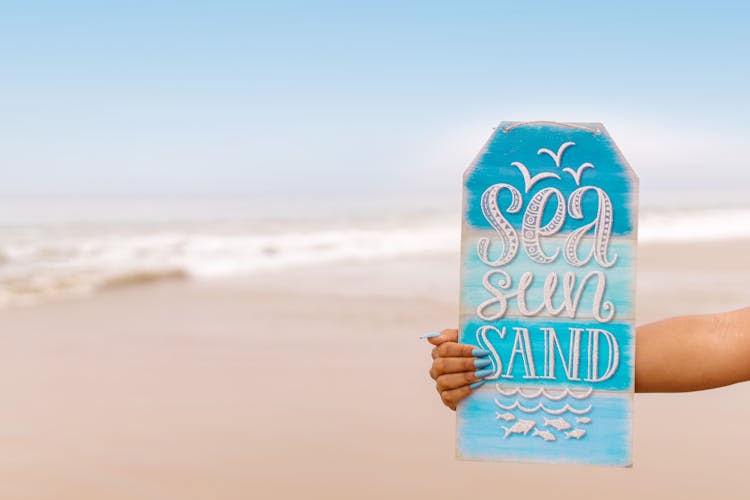 A Person Holding A Sign On The Beach