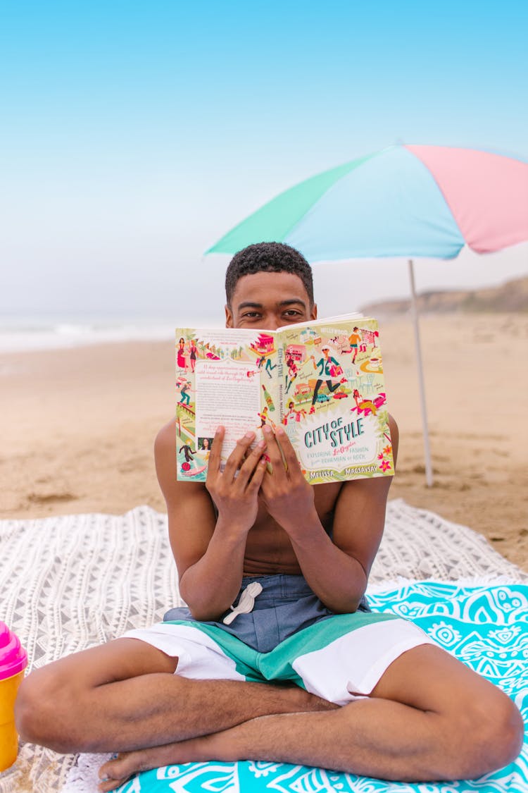 A Man Reading A Book In The Beach