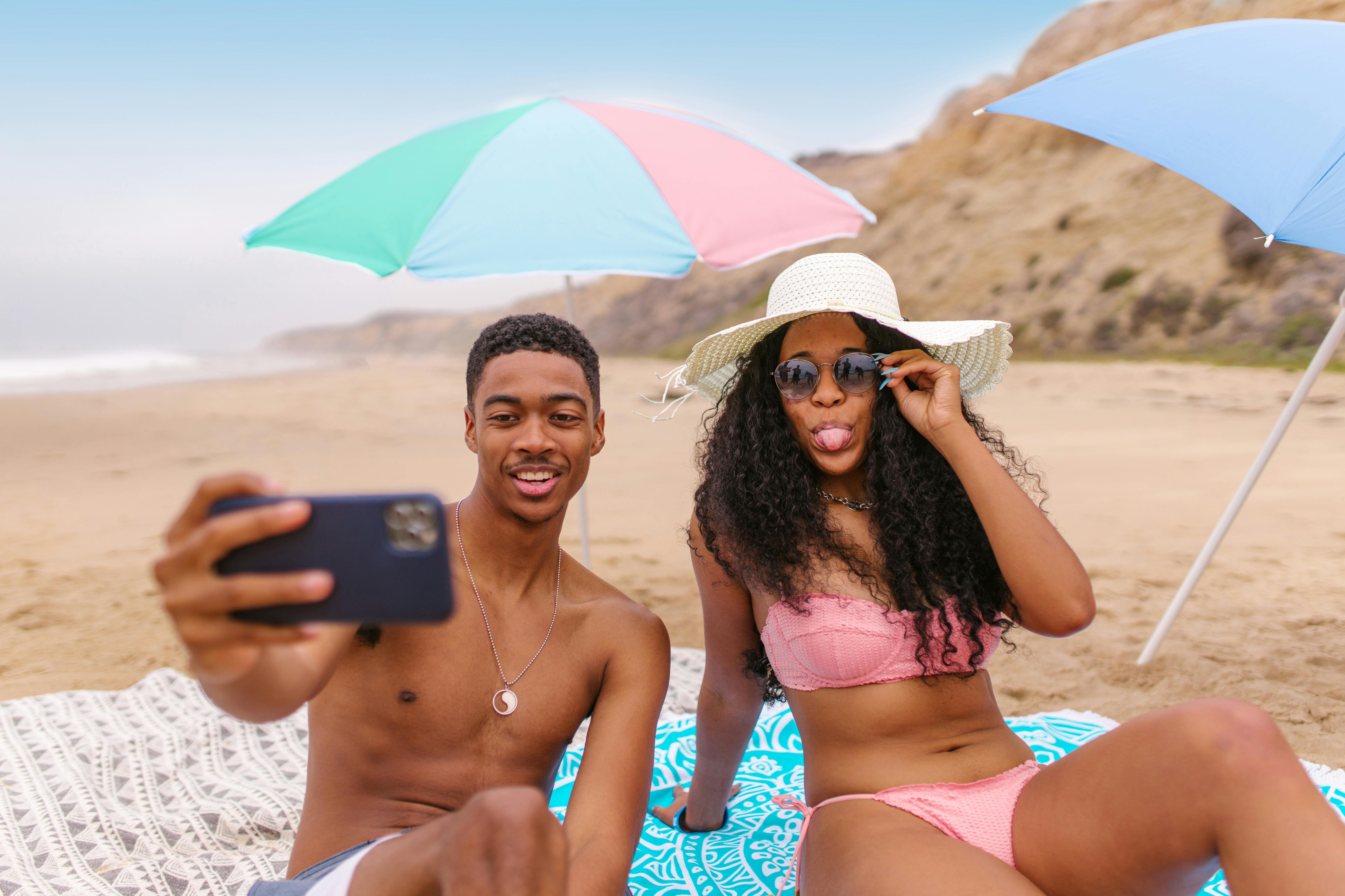 一对年轻夫妇在沙滩上享受阳光明媚的一天，自拍放松身心