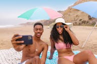 一对年轻夫妇在沙滩上享受阳光明媚的一天，自拍放松身心