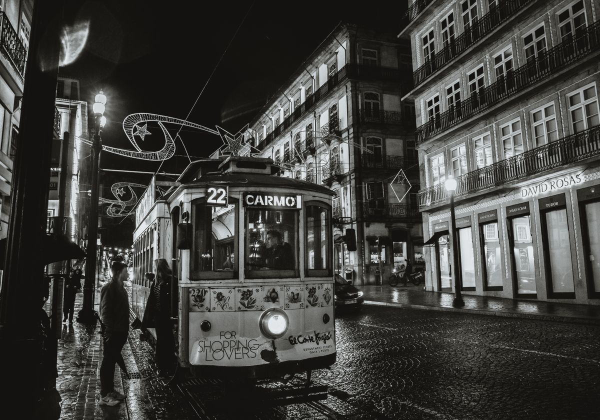 Black and white photo of a tram on Porto's streets at night, highlighting urban architecture.